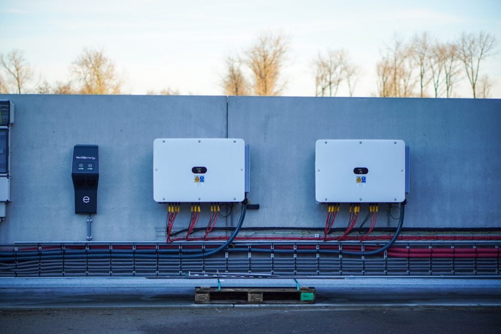 Elektriciteitsvoorziening met omvormers en kabels op muur voor duurzame energieoplossingen.