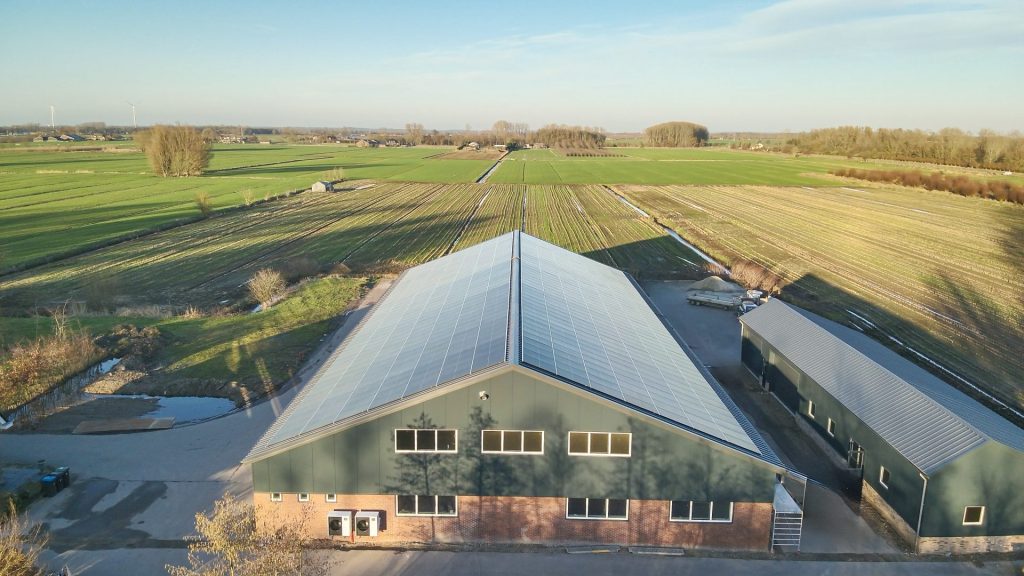 Zonnepanelen op bedrijfsgebouw in landelijke omgeving voor duurzame energie.